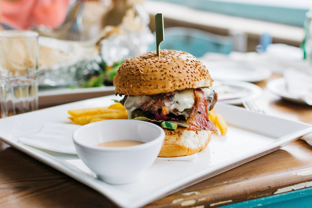 Burger con bacon e formaggio fuso servito con patatine